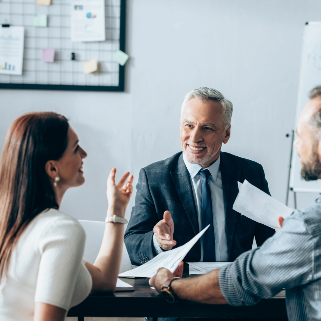 Three people around a conference table.