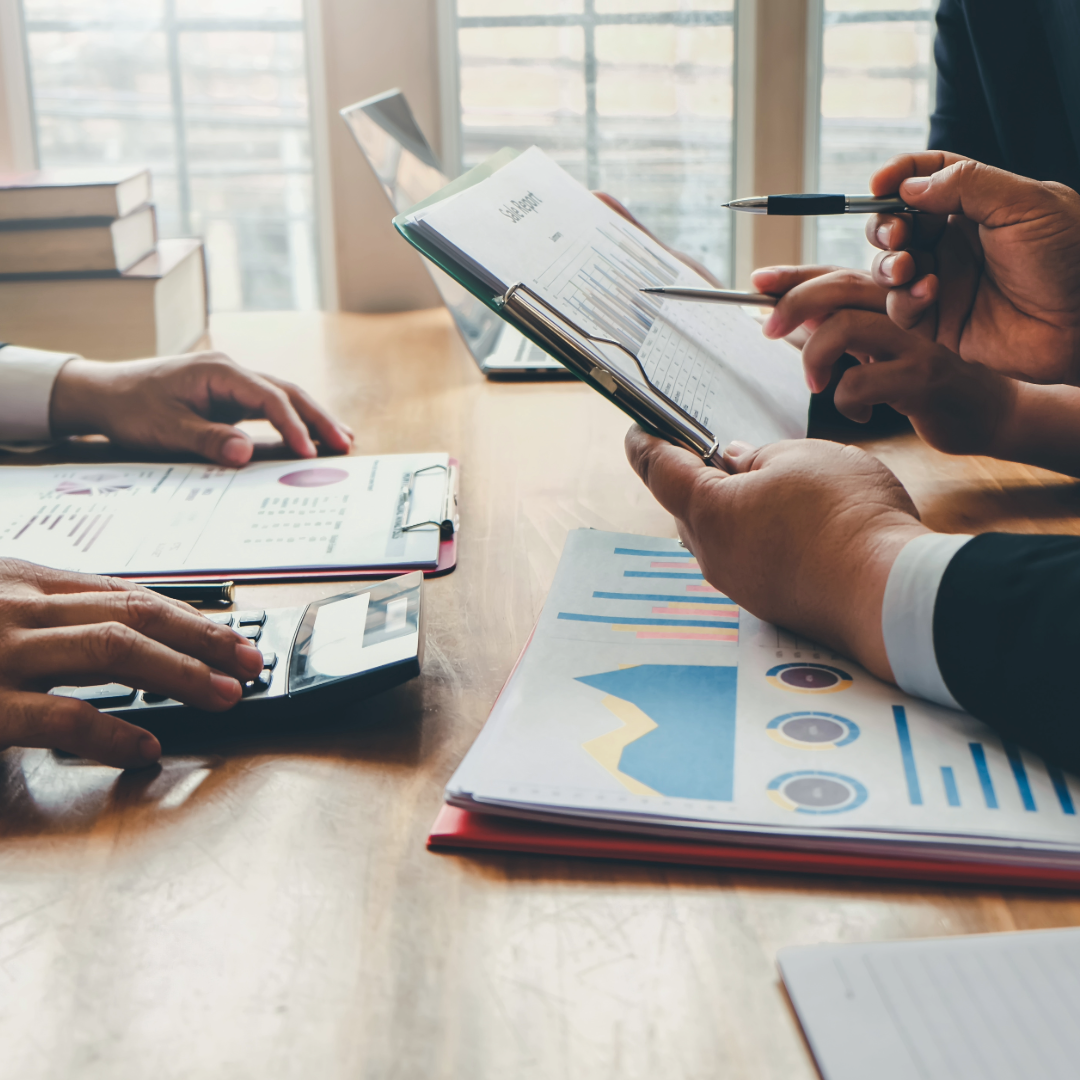 People at a desk with a calculator and graphs.