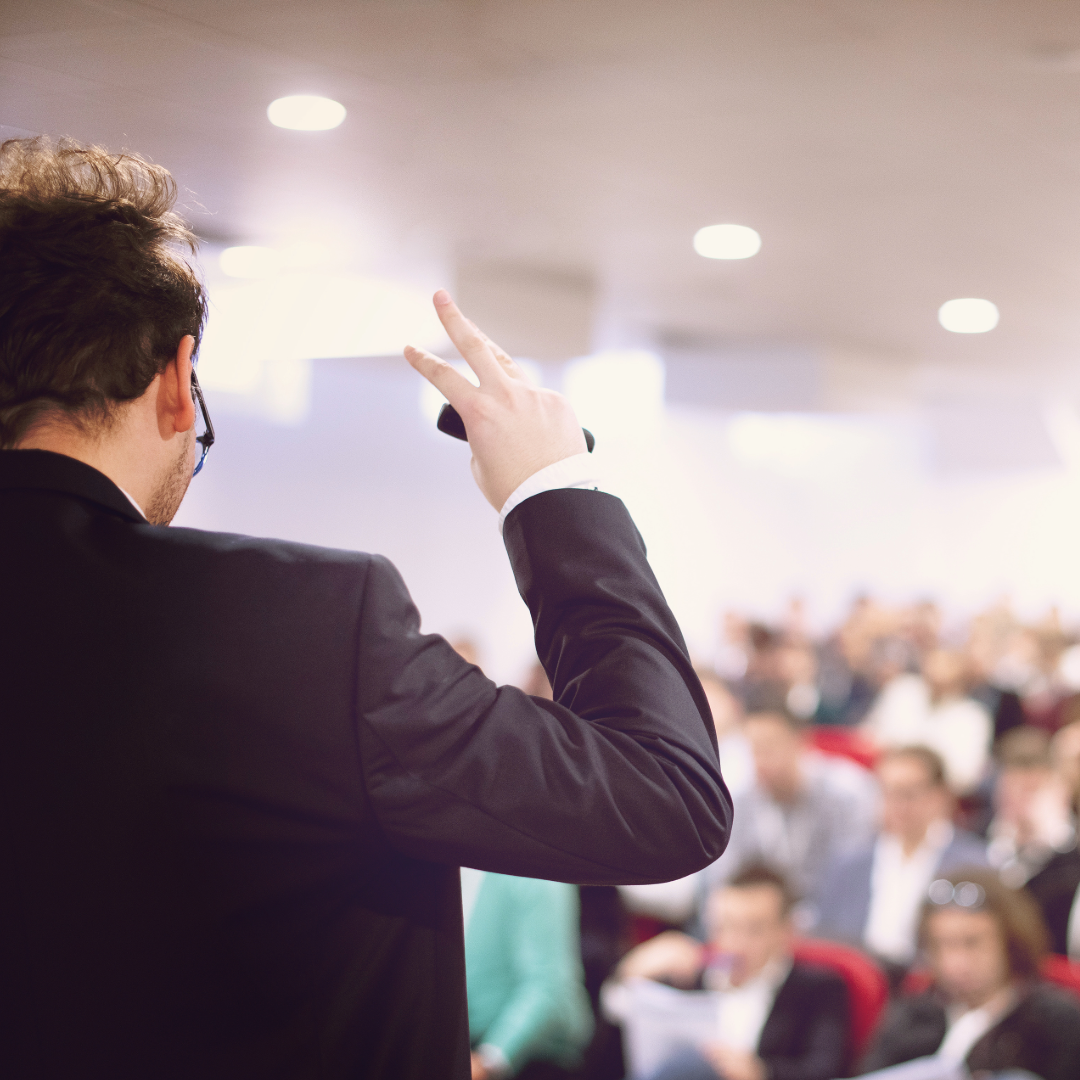 A figure gives a presentation in a conference hall.